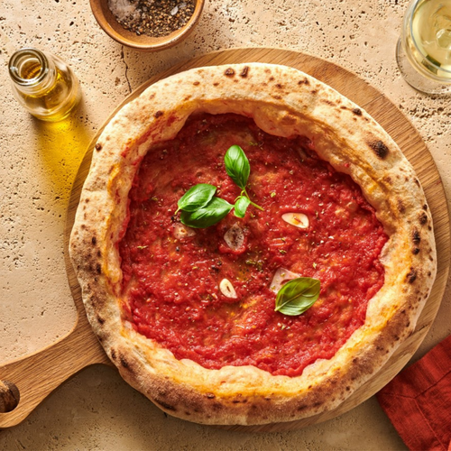 Eine traditionelle Pizza Marinara mit Tomatensauce, Knoblauch und Basilikum auf einem Holzbrett, mit Ölflasche daneben.