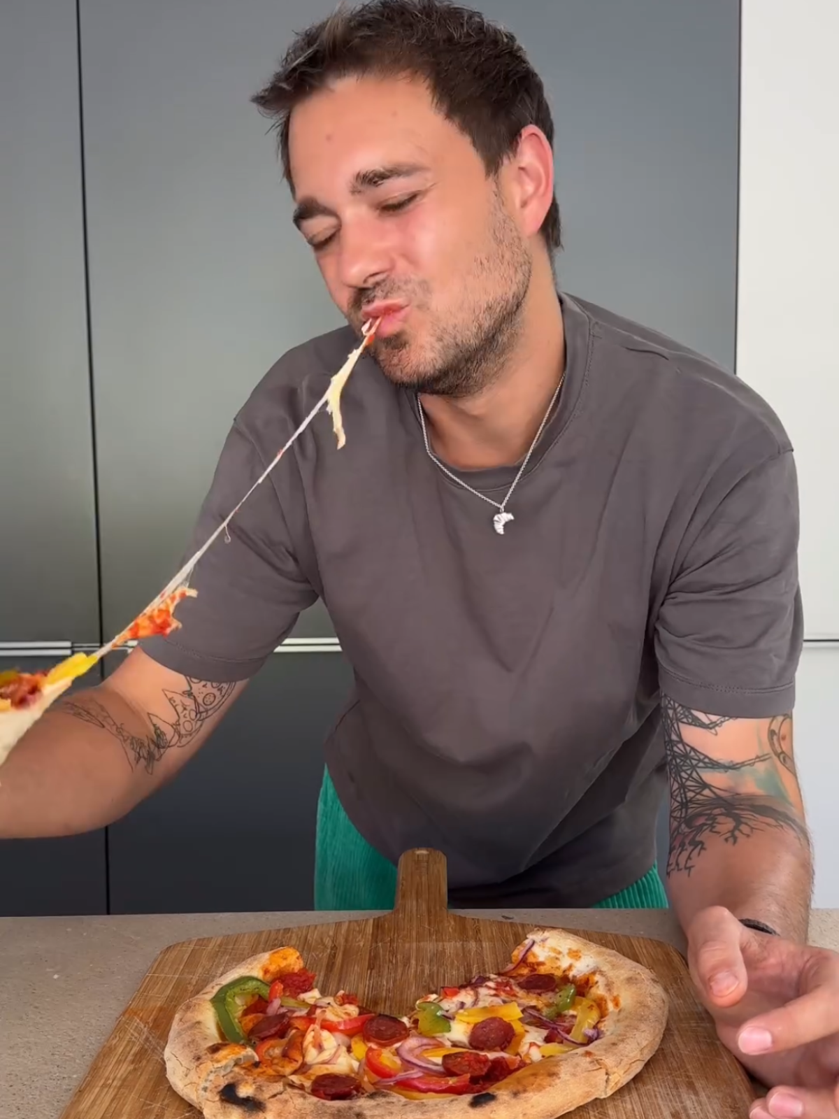 Ein Mann isst Pizza, während ein langer Faden geschmolzenen Käses von einem Stück herunterhängt.