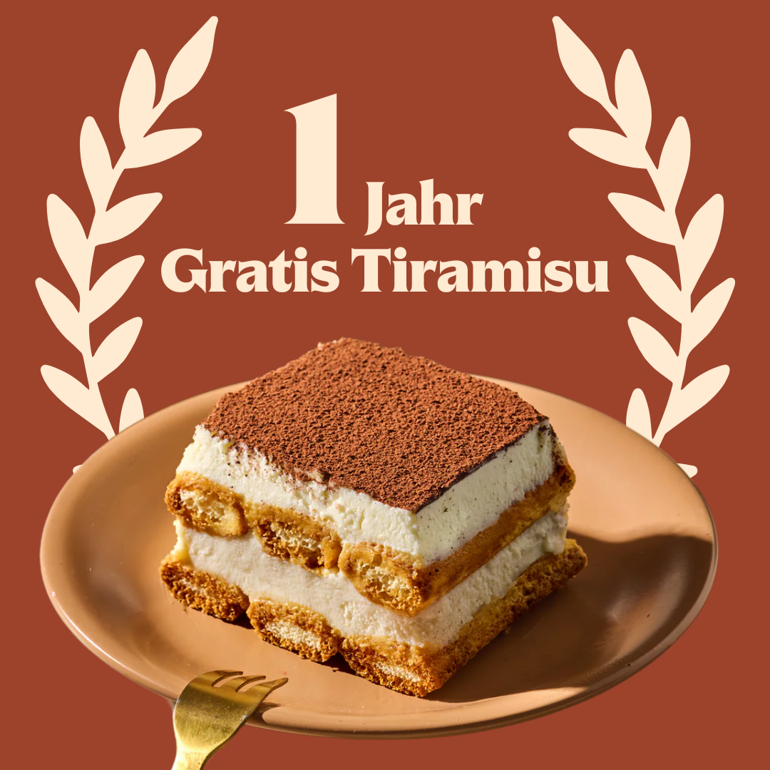 Tiramisu-Stück auf einem Teller mit der Aufschrift „1 Jahr Gratis Tiramisu“ im Hintergrund.
