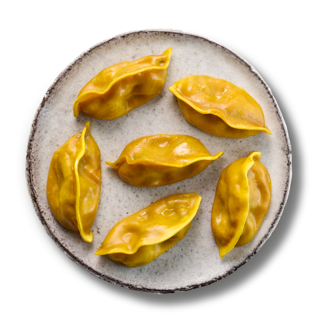 Sechs gelbe Teigtaschen auf einem rundem, hellen Teller vor schwarzem Hintergrund.