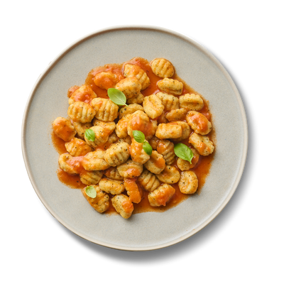 Ein Teller Gnocchi mit Tomatensoße und Basilikumblättern, aus der Vogelperspektive fotografiert.