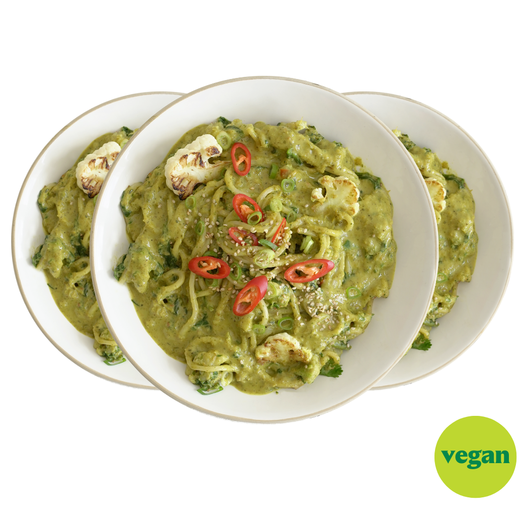 Drei Teller mit grüner veganer Pasta, garniert mit Chilis und Sesam, vor einem veganen Logo.