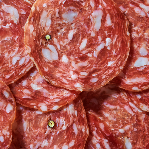 Nahaufnahme von mehreren Scheiben Salami mit sichtbaren Fettstückchen.