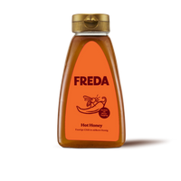Braune Flasche mit orangem Etikett der Marke "FREDA", beschriftet als "Hot Honey" mit einer Biene und einer Chilischote.