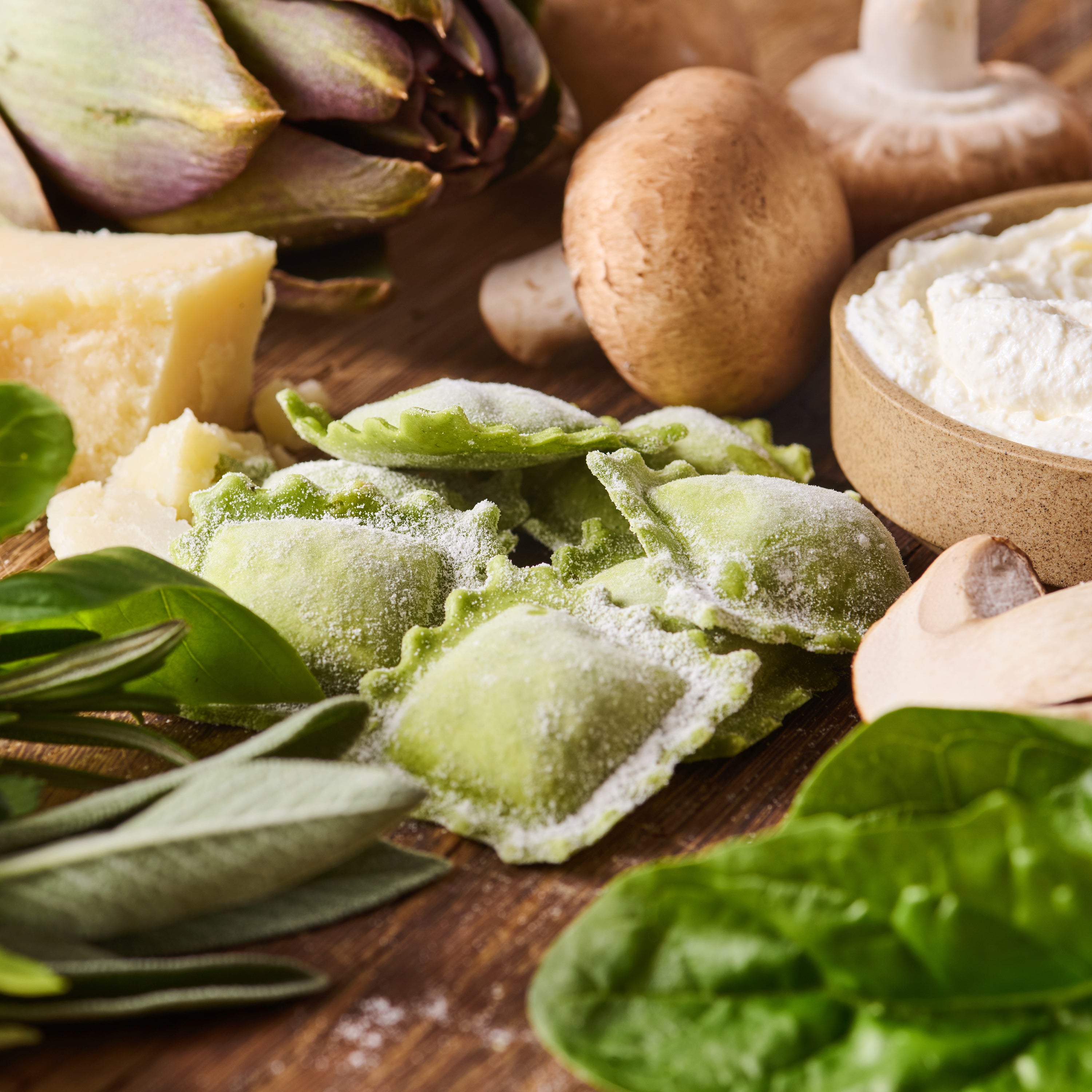 Frische grüne Ravioli mit Artischocken, Champignons, Ricotta und Parmesan auf einem Holztisch.