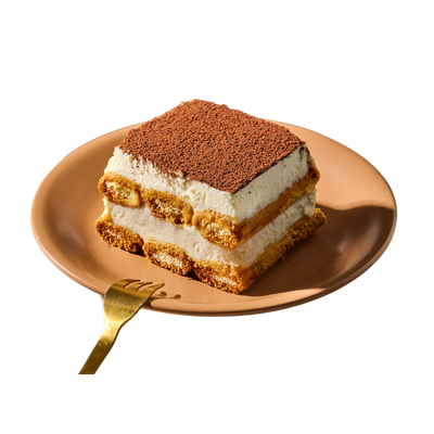 Ein Stück Tiramisu auf einem orangefarbenen Teller mit einer goldenen Gabel daneben.