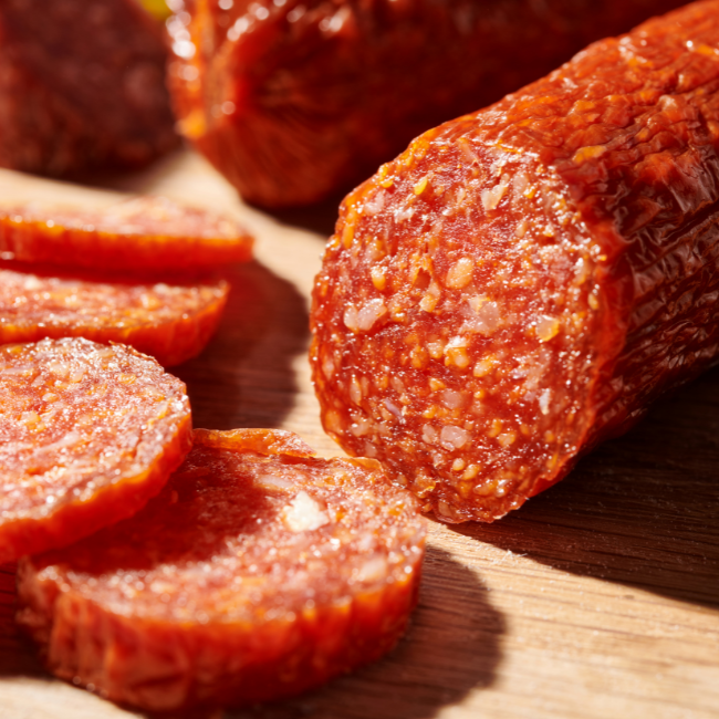 Geschnittene Salami auf einem Holzbrett, nah aufgenommen.