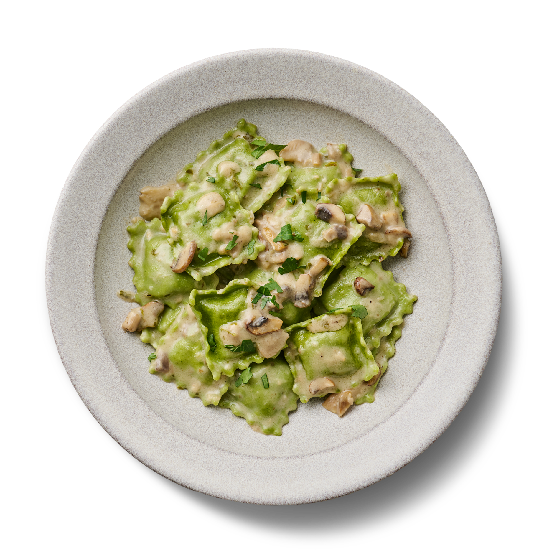 Grünes Ravioli-Gericht mit Pilzsahnesauce und Kräutern auf einem weißen Teller, vor schwarzem Hintergrund.
