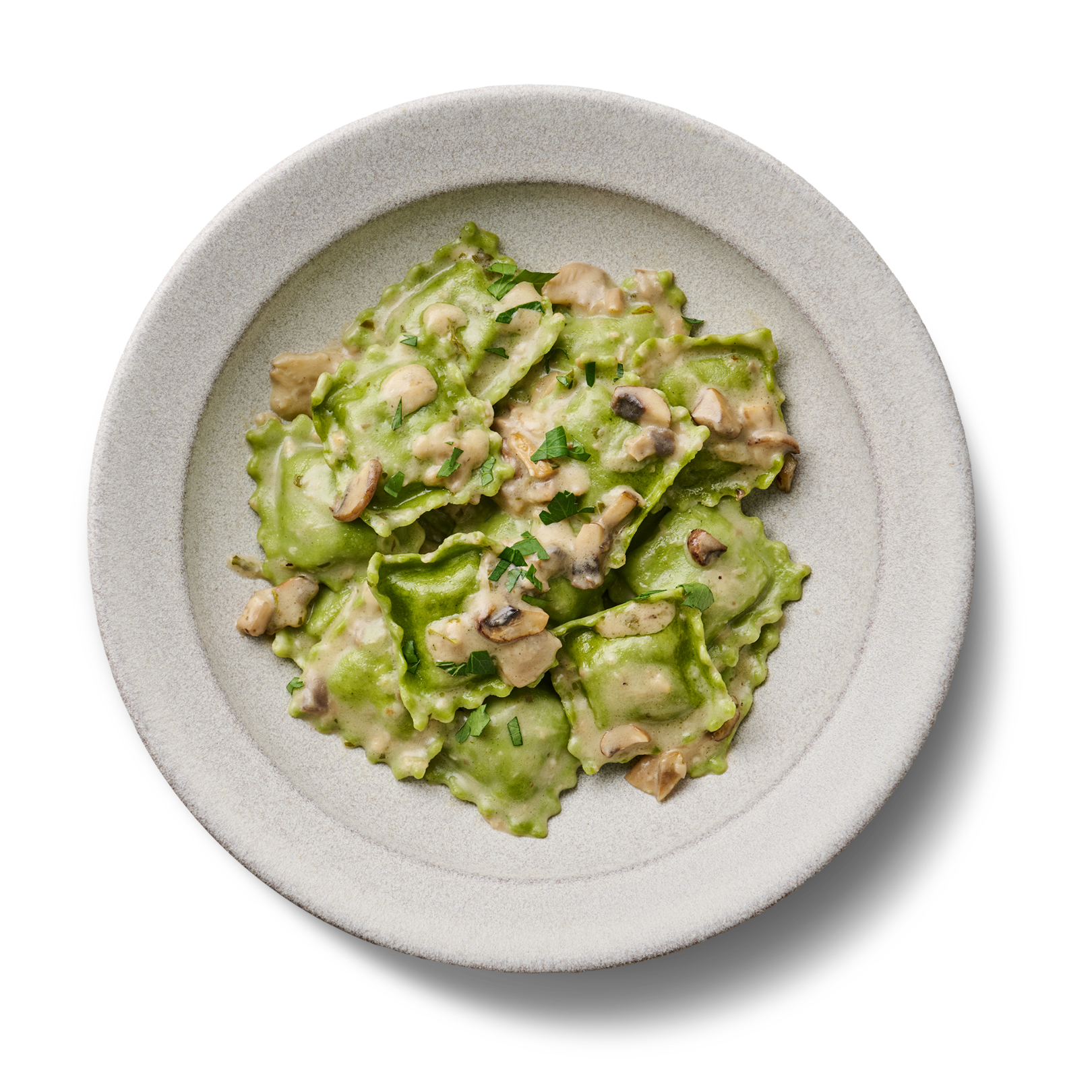 Ein Teller mit grünen Ravioli in Sahnesauce, garniert mit Pilzen und Kräutern.