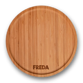 Runde Holzschneidebrett mit der Gravur "FREDA" am Rand, auf schwarzem Hintergrund.