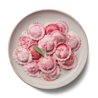 Teller mit rosa Ravioli in Sahnesoße, dekoriert mit einem Salbeiblatt.